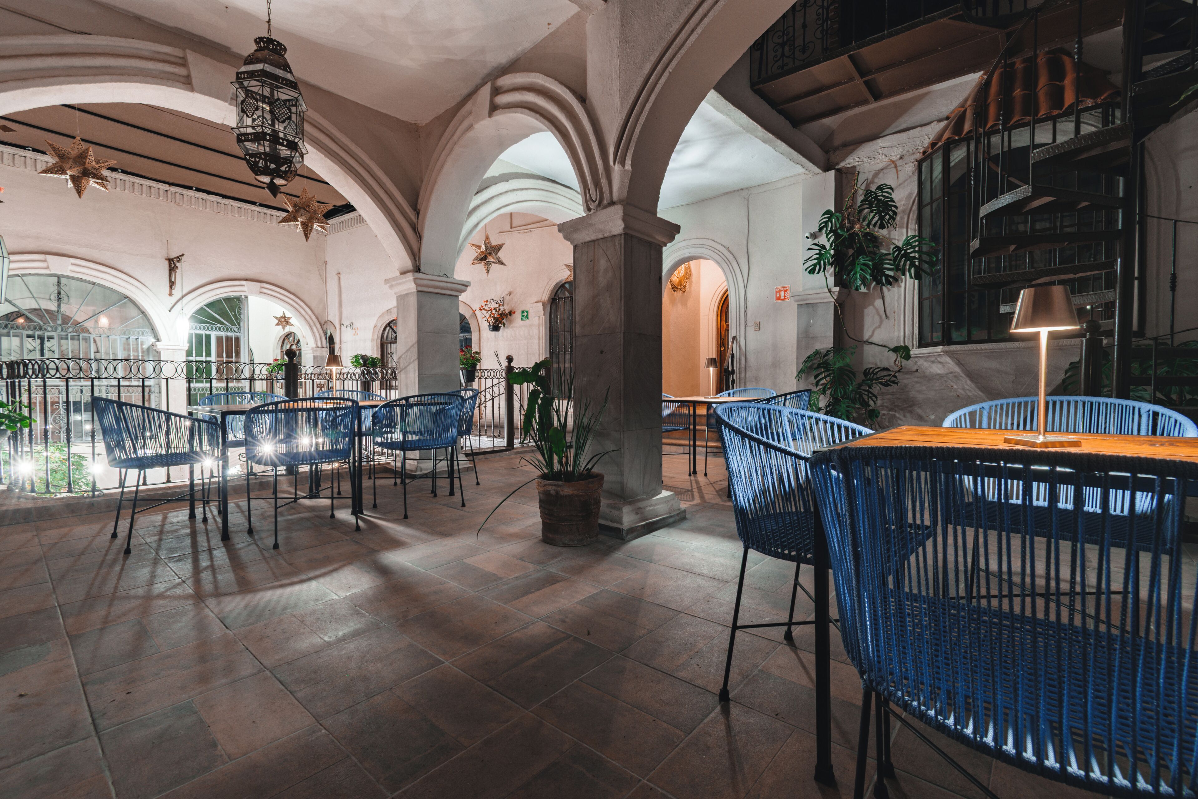 An indoor area with blue chairs, a table, and a hanging lantern.