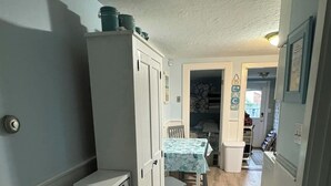 Un corridoio stretto con pavimento in legno, un tavolo con tovaglia blu e una porta bianca.