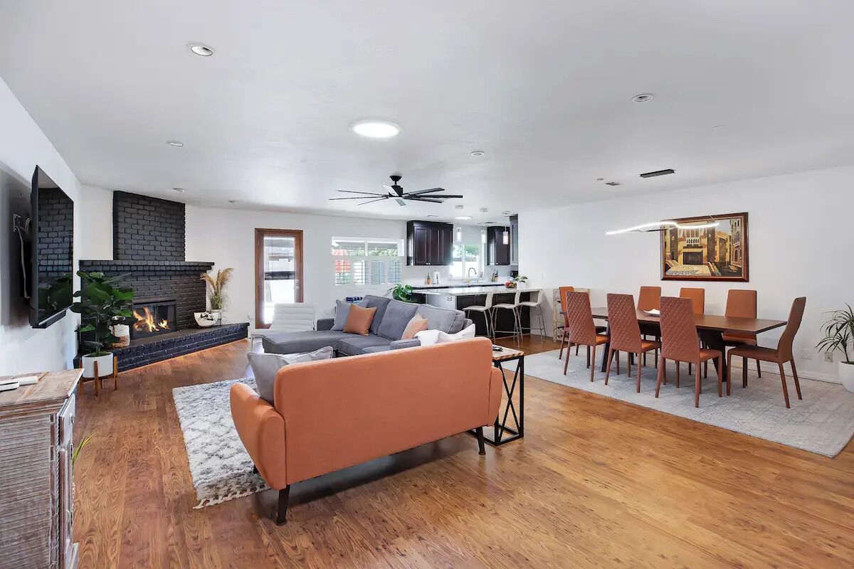 Una sala de estar amplia con chimenea, un sofá, un comedor con mesa y sillas, y una cocina al fondo.