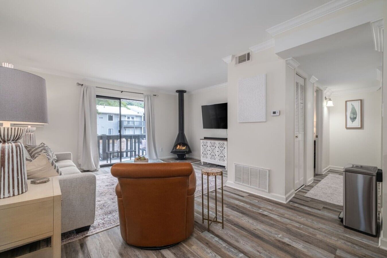 Una sala de estar con sofá, un reposapiés marrón, chimenea, televisión y una mesita.