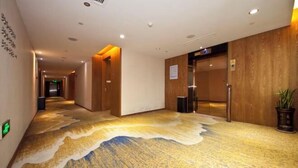 Ein Hotelgang mit einem einzigartigen Teppichdesign, Holzwänden und einem modernen Aufzug.