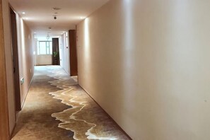 A hallway with a unique floor design, doors on both sides, and a window at the end. - WENZHOU JIAYAN HOTEL (Wenzhou)