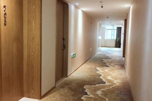 A hotel hallway with a carpeted floor, wooden doors, and a light switch on the wall. - WENZHOU JIAYAN HOTEL (Wenzhou)