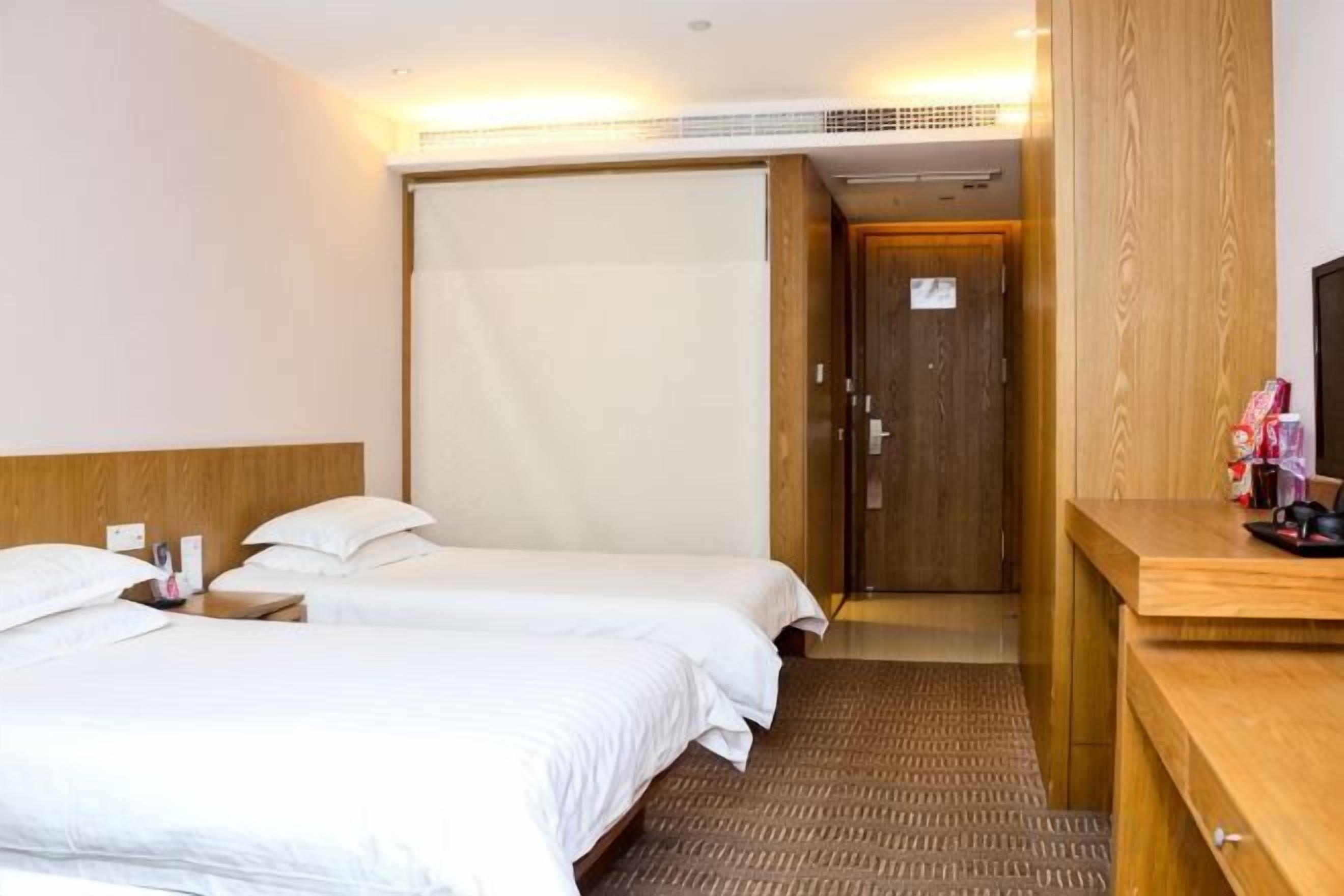Una habitación de hotel con dos camas, un escritorio de madera y una puerta que da a un baño.