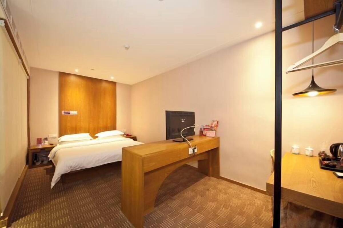 Une chambre d’hôtel équipée d’un lit, d’un bureau, d’une télévision et d’une petite table avec une bouilloire.
