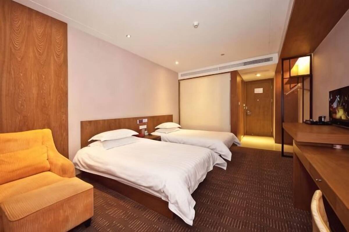Une chambre d’hôtel avec deux lits, un canapé, un bureau et une télévision.