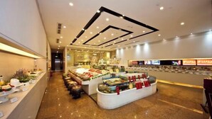 Un hall d’hôtel moderne avec un présentoir central où sont exposés des plats, un long comptoir d’accueil et un sol propre et bien ciré.