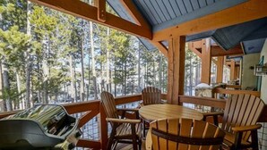 A wooden deck with a table and chairs, overlooking a forested area. - Premier 2 Bedroom Townhome Across From Snowflake Lift - Walk to Lifts (Breckenridge)