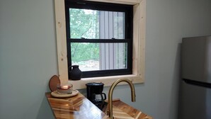 Eine Küche mit einer Holz Arbeitsplatte, einem Fenster mit Blick auf Grünflächen, einer Spüle und einem Kühlschrank.