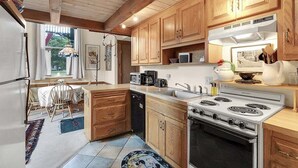 A kitchen with wooden cabinets, a stove, a microwave, and a dishwasher. - Opera House Loft 02 - Bethel Village (Bethel)