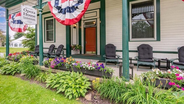A building with a porch, outdoor seating, and a flag. - Opera House Loft 02 - Bethel Village (Bethel)
