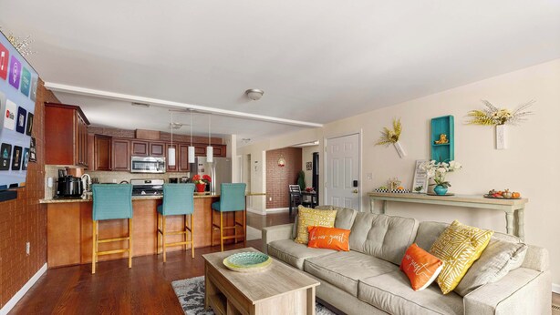A modern living room with a sofa, coffee table, and kitchen area in the background.