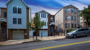 A row of townhouses with a garage, a gated entrance, and a car parked on the street.