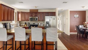 Una cocina moderna con armarios de madera oscura, electrodomésticos de acero inoxidable y una zona de bar con sillas tapizadas.