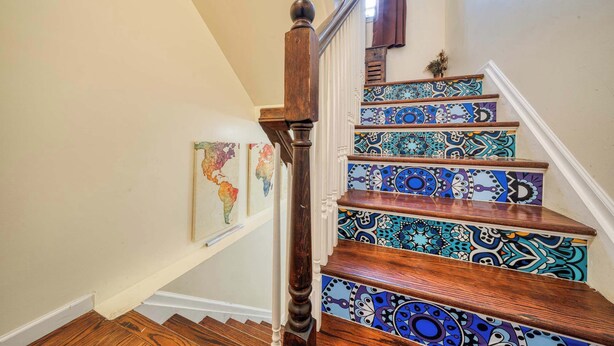 Una escalera de madera con escalones de diseño colorido y barandilla de madera.
