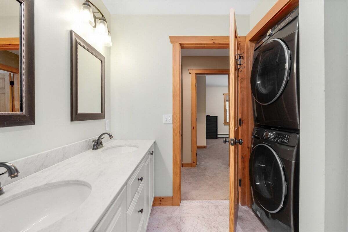 A bathroom with a double sink, a mirror, and a washing machine.