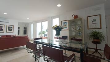 Un comedor moderno con una mesa de vidrio, sillas de metal y un sofá rojo.