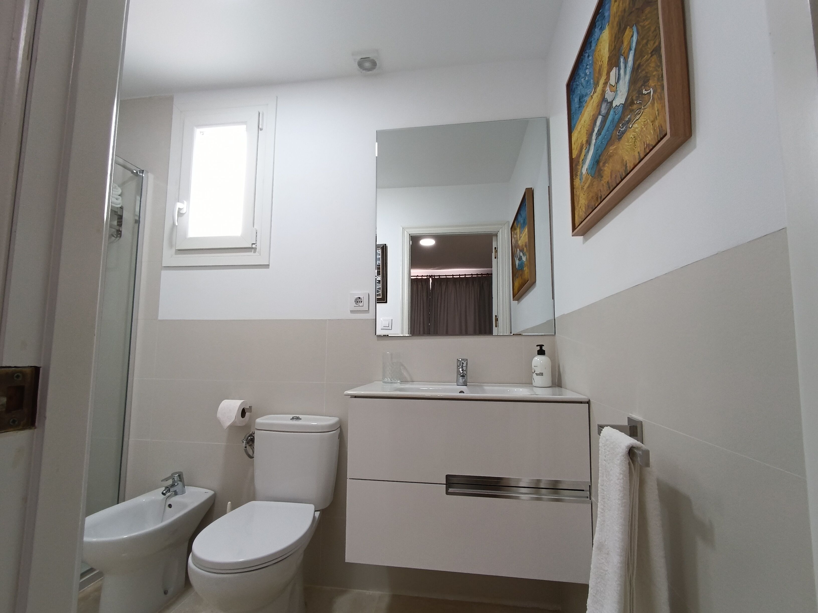 A bathroom with a toilet, bidet, sink, and mirror.