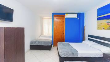 A bedroom with two beds, a wardrobe, a TV, and an air conditioner.