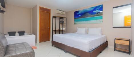 A bedroom with a bed, a sofa, a small table, and a painting on the wall.