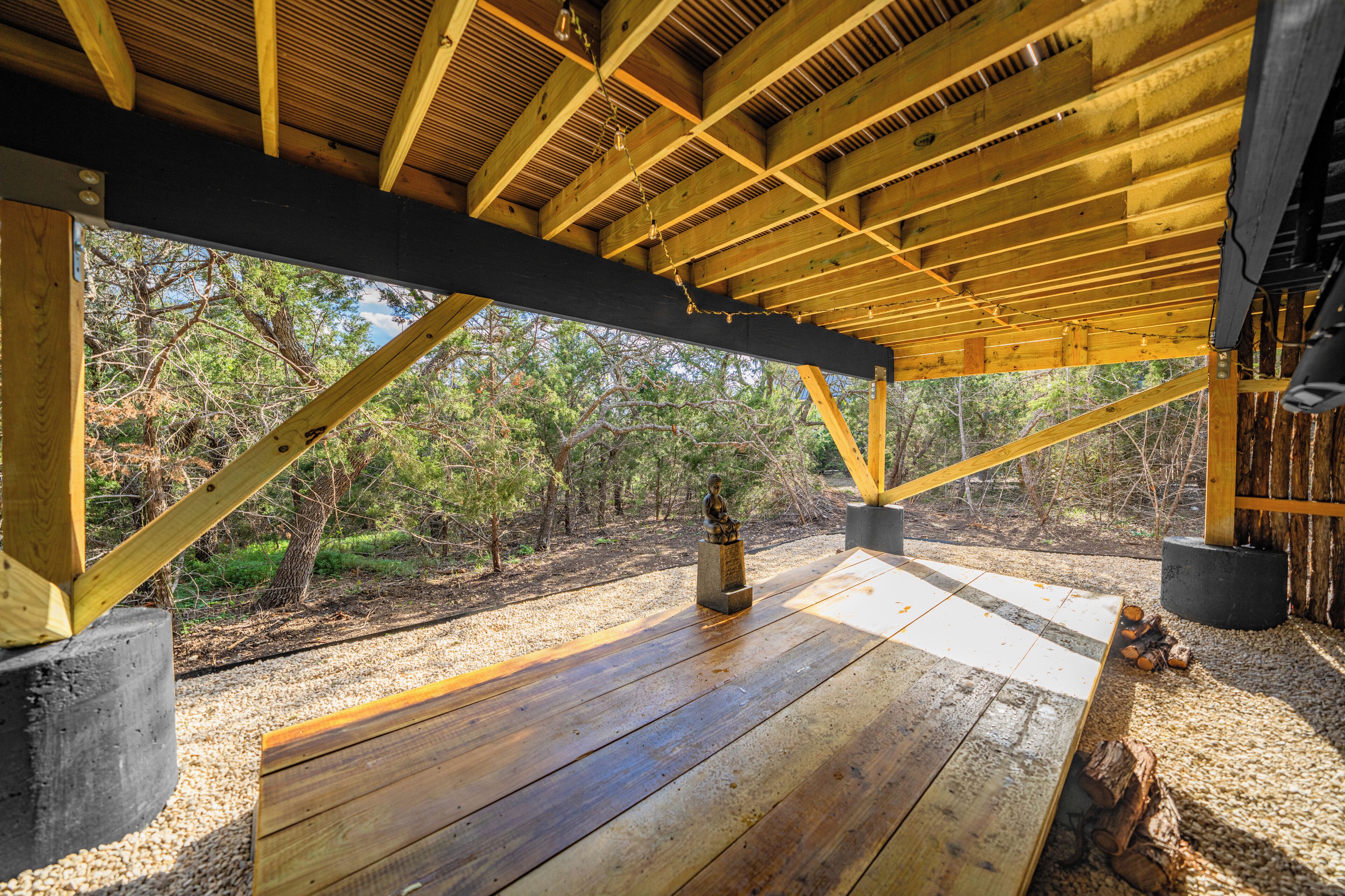 Une terrasse en bois, sans toit, offrant une vue sur une forêt.