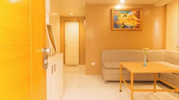 Ein Hotelzimmer mit Holztür, einem beigen Sofa, einem kleinen Holztisch und einem Gemälde an der Wand.