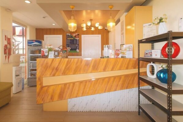A reception area with a wooden reception desk, a coffee machine, and a shelf with decorative items.