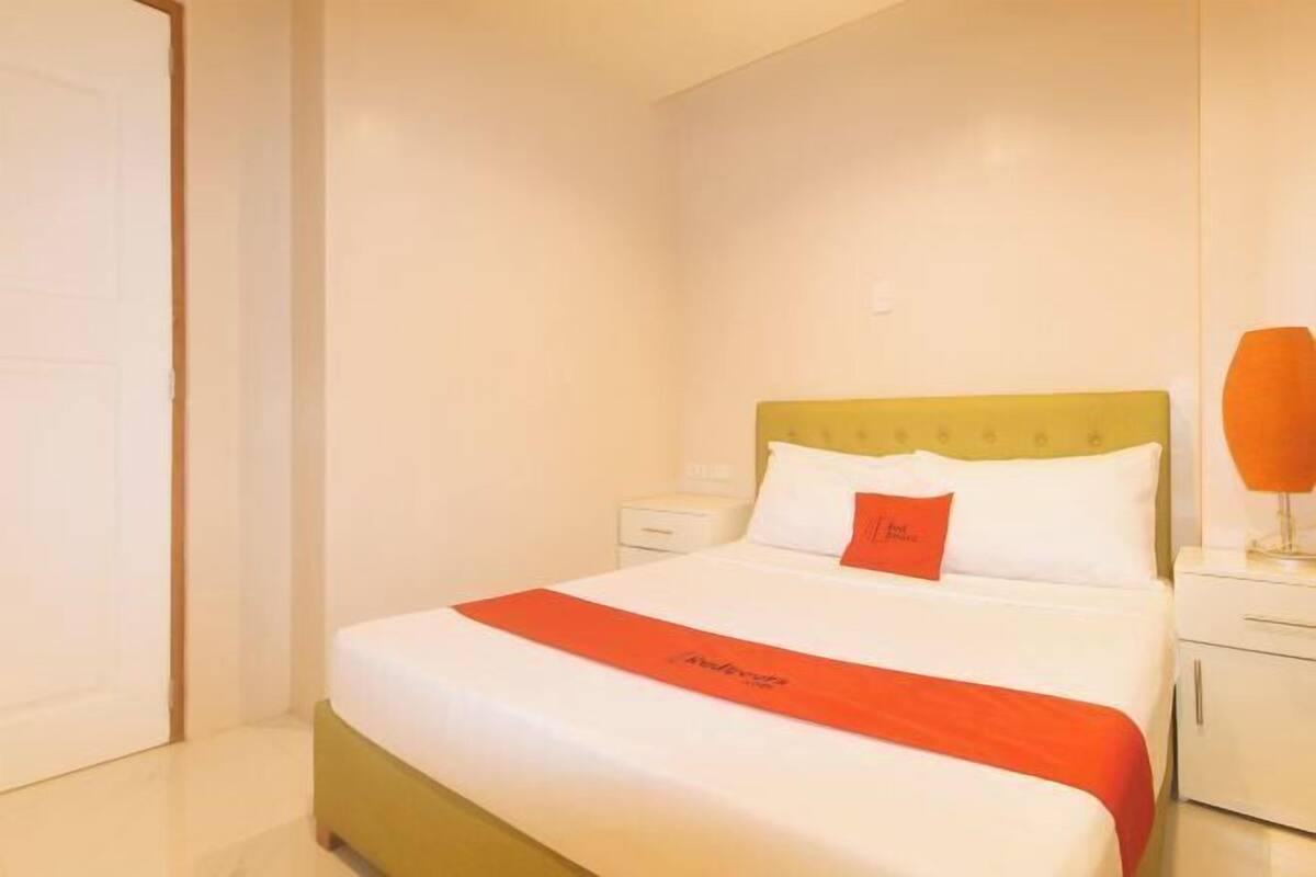 Een hotelkamer met een bed, nachtkastje en lamp.
