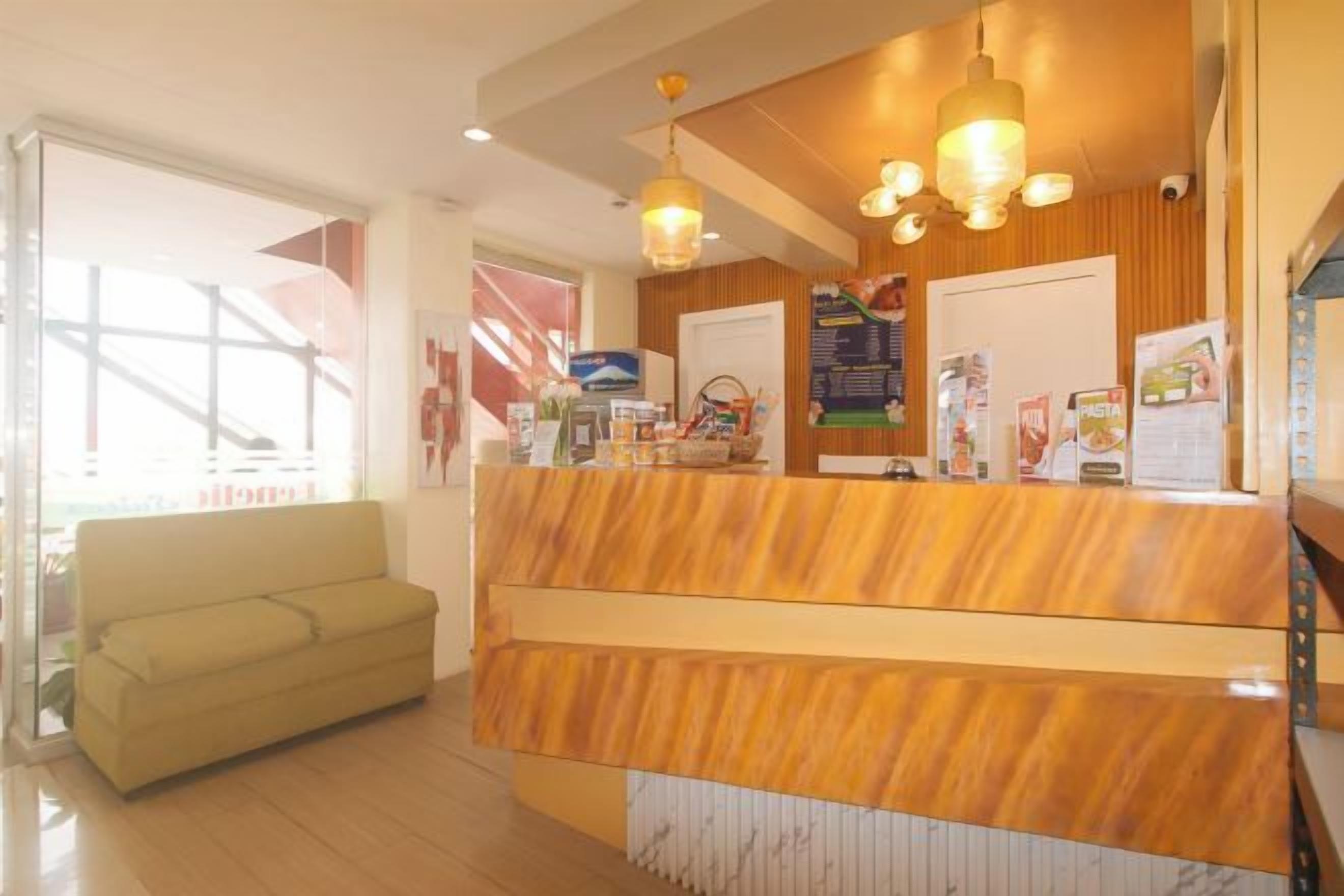 A reception area with a wooden reception desk, a sofa, and a large window.