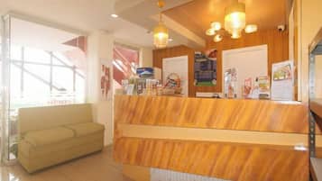 A reception area with a wooden reception desk, a sofa, and a large window.