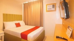 Ein Hotelzimmer mit Bett, Nachttisch, Fernseher und einer Wandpaneele aus Holz.