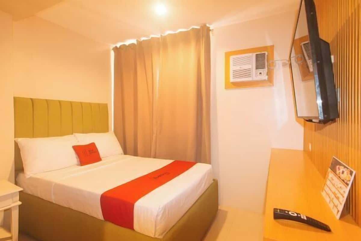 Een hotelkamer met een bed, nachtkastje, televisie en een wand van hout.