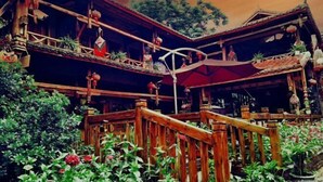 Un bâtiment traditionnel en bois, doté d’un balcon, de plantes en pot et de décorations suspendues.