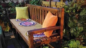 Un banc en bois agrémenté de sets de table et de coussins aux couleurs vives.