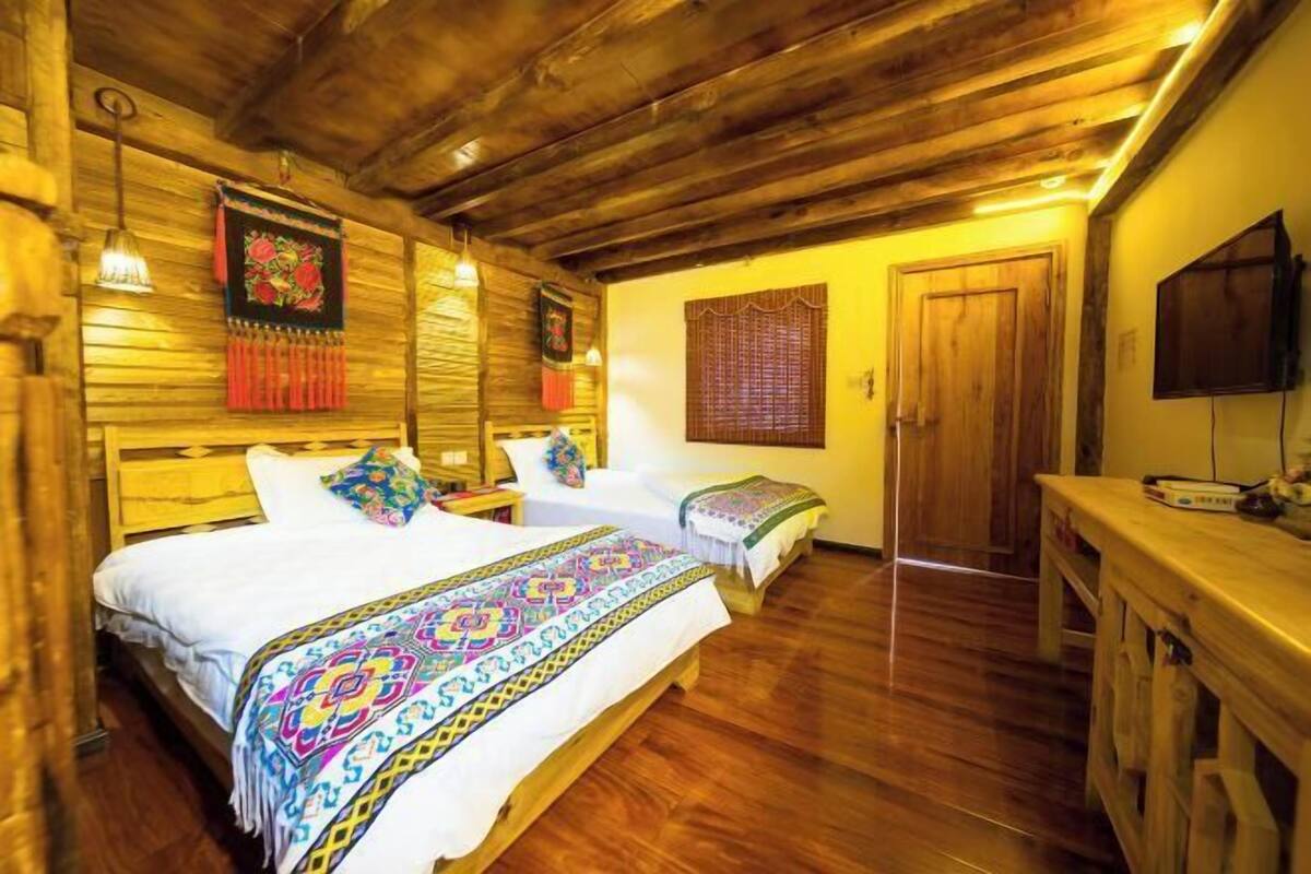Um quarto estilo cabana de madeira com duas camas, teto de madeira e uma televisão sobre um suporte de madeira.