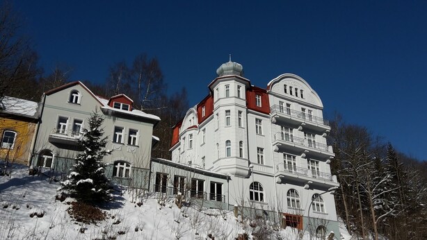 A large, multi-story building with a classic architectural style, featuring a prominent dome and multiple balconies. - Apartmánový Komplex Dagmar (Jachymov)