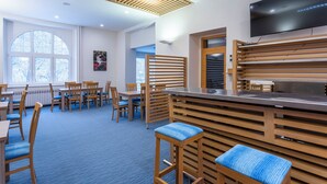 A modern restaurant with wooden furniture, a flat-screen TV, and large windows. - Apartmánový Komplex Dagmar (Jachymov)