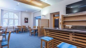 A modern restaurant with wooden furniture, a flat-screen TV, and large windows.