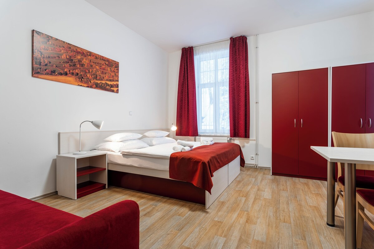 A modern bedroom with a bed, bedside table, and a red wardrobe.