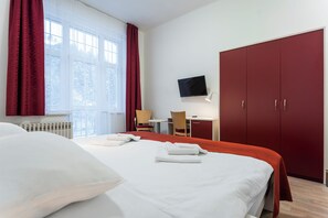 A hotel room with a bed, a desk, a chair, a TV, and a wardrobe. - Apartmánový Komplex Dagmar (Jachymov)