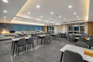 A modern dining area with tables and chairs, a kitchen counter, and a blue-tiled backsplash. - Wanbang Zundi Hotel (Xi'an High-tech Wanda Plaza Mutasi Subway Station Branch) (Xi'an)