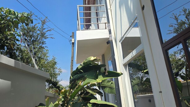 Un pasillo estrecho con una antena parabólica, paredes blancas y un pequeño balcón.