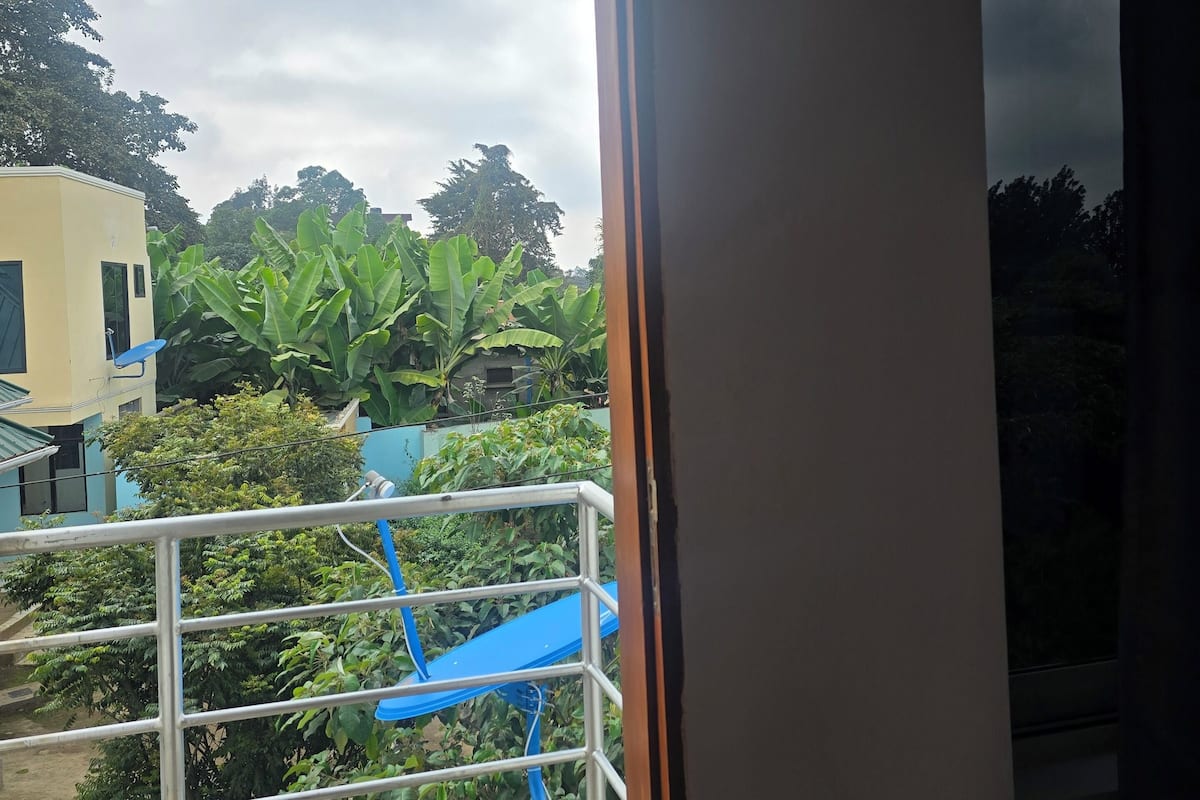 A balcony with a view of a building and lush greenery.