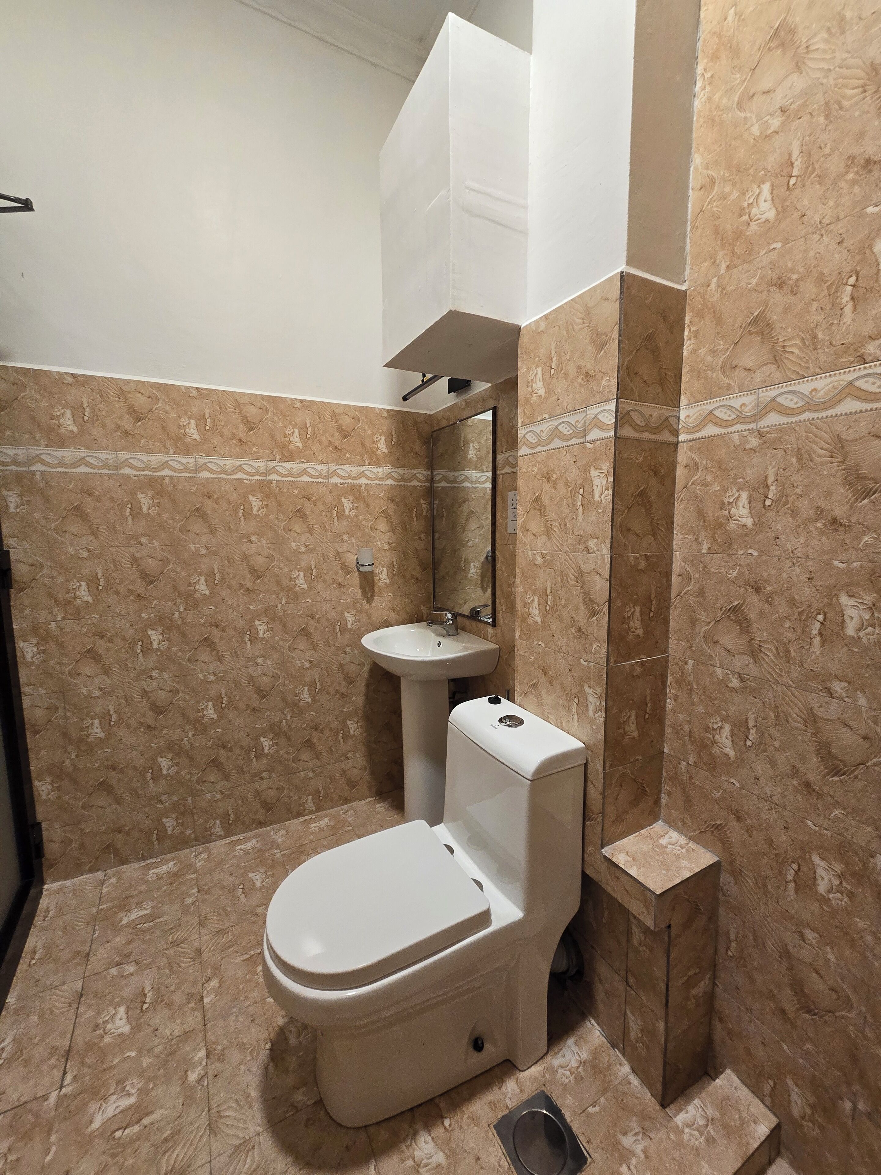 A bathroom with a toilet, sink, and mirror.