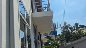 Un sendero estrecho que conduce a un edificio con balcón y antena parabólica.