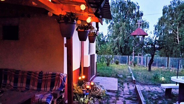 Un edificio con un porche cubierto, mesas al aire libre e iluminación colgante.