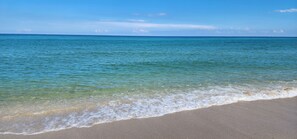 A beach with clear turquoise water and a sandy shore.