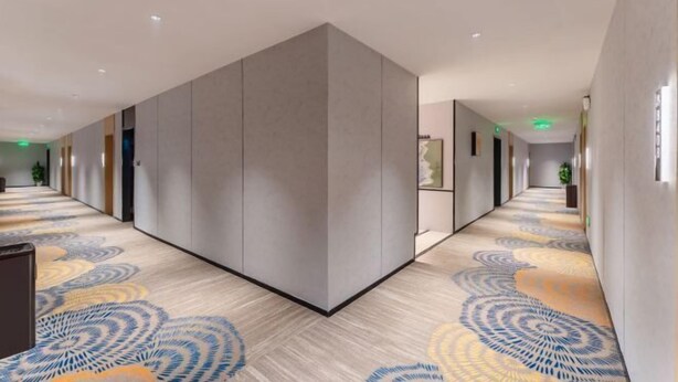 A modern hotel corridor with a patterned carpet, neutral walls, and a large grey partition. - Xiangtan Jinguiyuan Hotel (Government City Wanda Plaza) (Xiangtan)