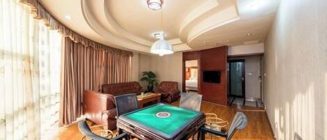 A room with a pool table, leather chairs, a sofa, and a ceiling light fixture.