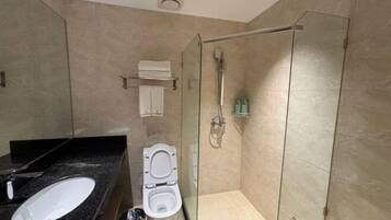 A modern bathroom with a glass-enclosed shower, a white toilet, and a black countertop with a sink.